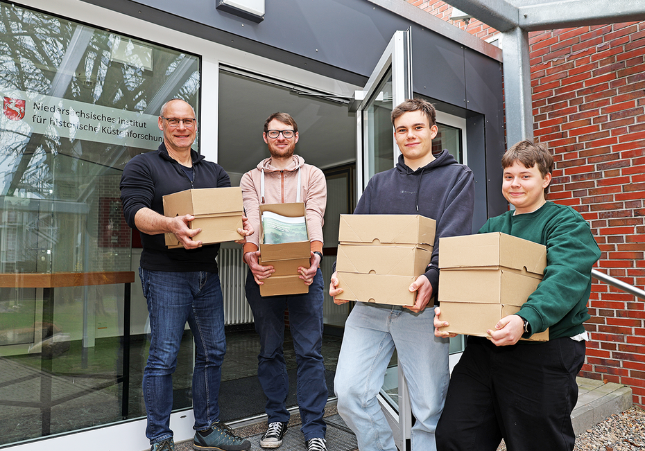 Vier Personen tragen Kartons in das Gebäude des NIhK