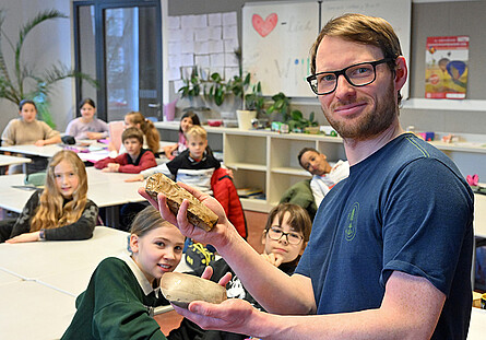 Moritz Mennnenga zeigt Schülern ein Steinbeil