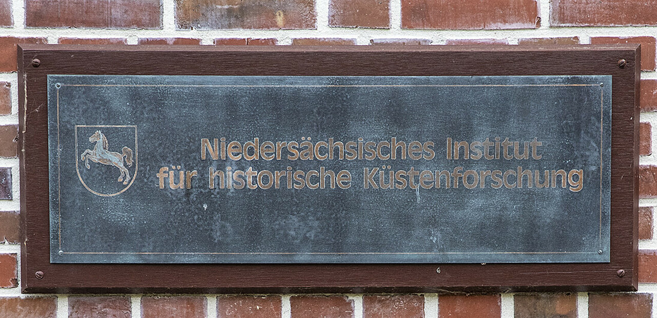 Metallschild mit Institutsbezeichnung an Klinkerwand des Gebäudes