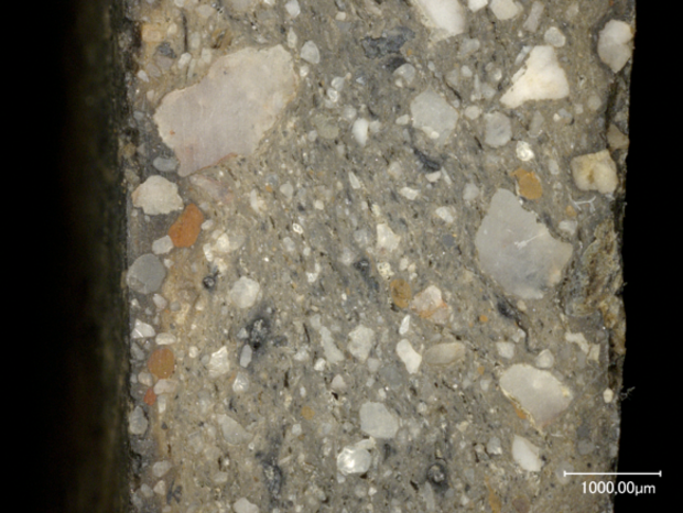 Makroaufnahme einer geschliffenen Fläche, man sieht verschidene Sandkörner und winzige Steinchen
