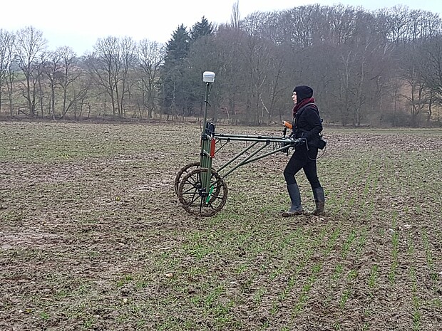 Grabungstechniker schiebt ein Messgerät über einen winterlichen Acker