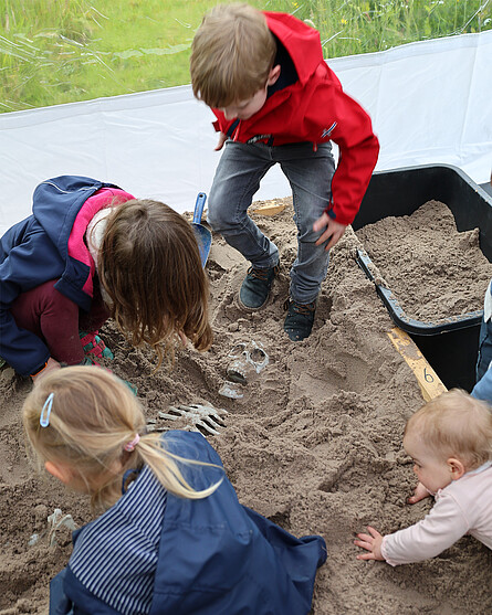 [Translate to Englisch:] Kinder buddeln im Sand, man sieht ein Kunststoffskelett