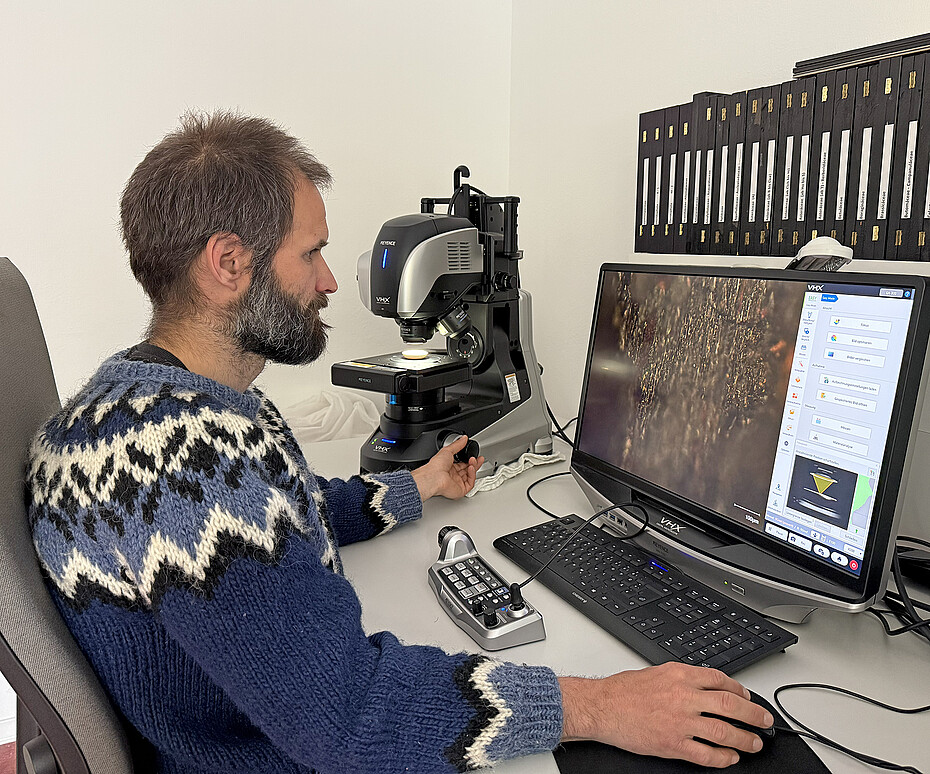 Jonathan Baines sitzt vor einem digitalen Mikroskop.